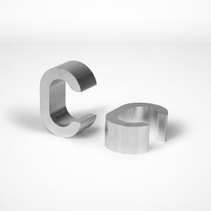 Two Talunet C-type Clamps are placed on a white surface. One clamp stands upright while the other lies flat, showcasing their curved design and smooth texture, reminiscent of wire rope equipment. Commonly used in the Gerro™ Combi system. © Copyright Talurit AB. All rights reserved.