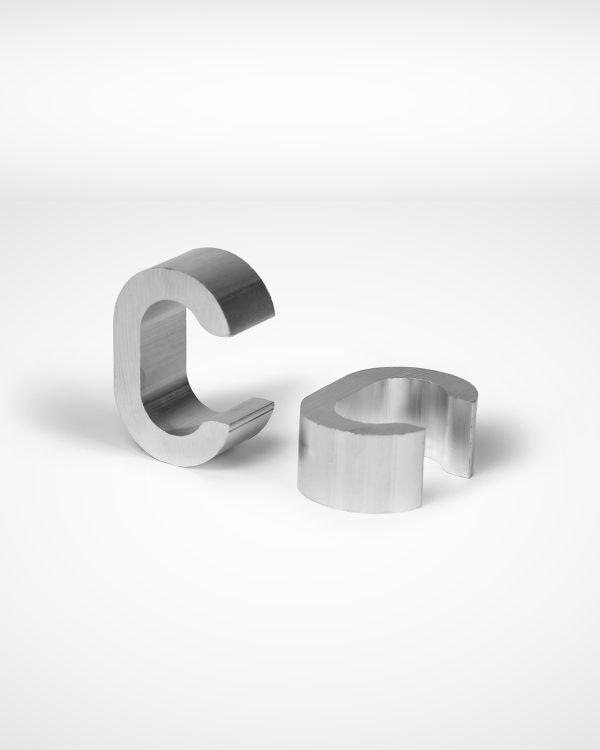 Two Talunet C-type Clamps are placed on a white surface. One clamp stands upright while the other lies flat, showcasing their curved design and smooth texture, reminiscent of wire rope equipment. Commonly used in the Gerro™ Combi system. © Copyright Talurit AB. All rights reserved.