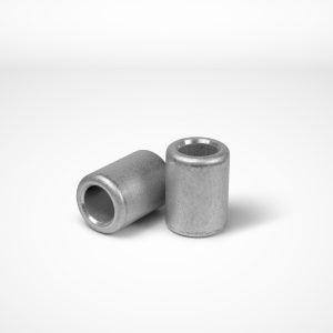 Two stop ferrules from the Talurit Group are placed on a white surface. One is standing upright while the other is lying on its side, clearly displaying the central hole that runs through each clamp. Ideal for mechanical splicing of combination wire rope, their surfaces and edges appear smooth and well-machined. © Copyright Talurit AB. All rights reserved.