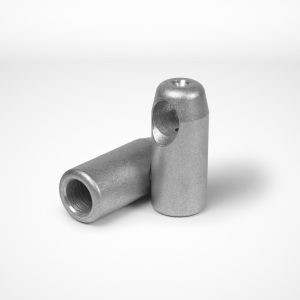 A pair of T-cross Joint Ferrules, used in combination wire rope applications, is displayed on a plain white background. One ferrule is standing upright, while the other lies horizontally beside it. Each has a drilled hole at one end and features a hollow cylindrical shape. © Copyright Talurit AB. All rights reserved.