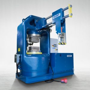 Talurit® The 4200T swager, a large blue industrial swager with a compact design, is shown. It features a robust frame, a horizontal arm called rigging device. This swager is placed on a clean, light-colored floor, with a power cable extending from its base. © Copyright Talurit AB. All rights reserved.