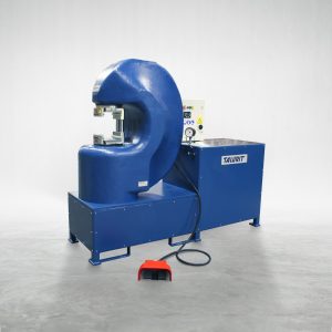 Talurit® A blue industrial machine labeled "600T 1S - Swager" is positioned on a gray floor. This wire rope equipment features a large, curved section and a control panel with various buttons. A black cable is attached, leading to a red foot pedal, ideal for mechanical splicing of wire rope. © Copyright Talurit AB. All rights reserved.