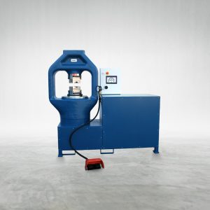Talurit® A blue **600T 2S - Swager** industrial hydraulic press machine is placed on a concrete floor in front of a plain white background. Designed for mechanical splicing of wire rope, the **600T 2S - Swager** features an attached control box and foot pedal for streamlined operation, making it ideal for handling ferrules and other wire rope equipment. © Copyright Talurit AB. All rights reserved.