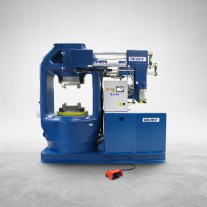 Talurit® The 3000T - Swager from the Talurit Group is an industrial machine with blue and white components, featuring a central press for mechanical splicing of wire rope, with electronics and controls located on the right side. The machine prominently displays the "TAURIT" brand name and has a red foot pedal positioned in front. © Copyright Talurit AB. All rights reserved.
