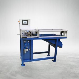 An LKA 04 AM – Automatic Annealing Machine from Talurit Group sits on a light gray floor with a plain white background. This blue industrial machine features various metal components, including multiple levers and adjustment knobs, and is equipped with a touchscreen control panel. © Copyright Talurit AB. All rights reserved.