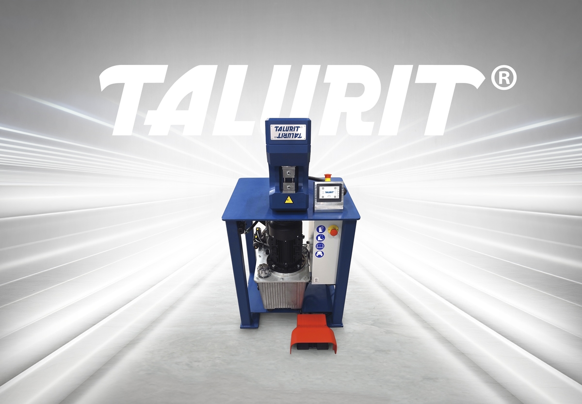 Talurit-50T-Swager-Product-photo-for-post-1200px Talurit® A blue industrial swager machine with a touchscreen display and foot pedal. Behind it is a large "TALURIT" logo with a radiant background. © Copyright Talurit AB. All rights reserved.